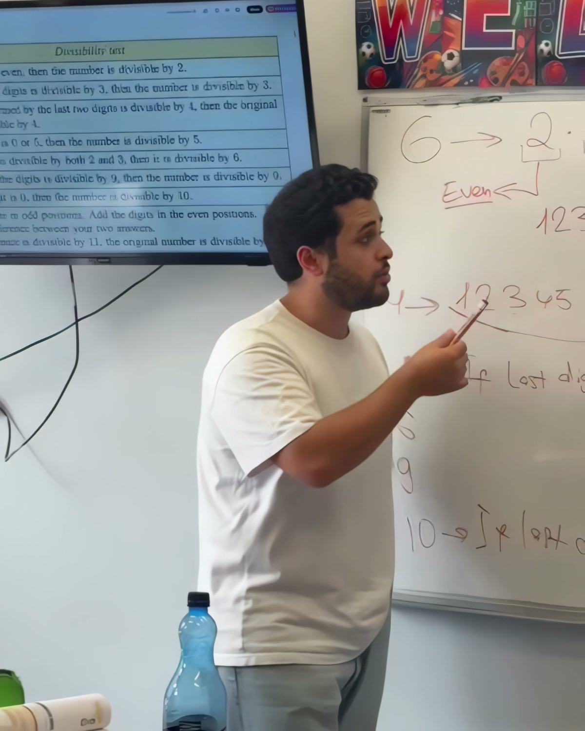 A teacher at IAS Warsaw explaining divisibility rules at the whiteboard in a maths lesson