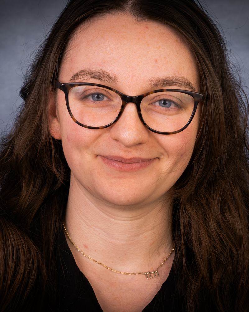 A smiling teacher at IAS Warsaw wearing glasses, studio portrait