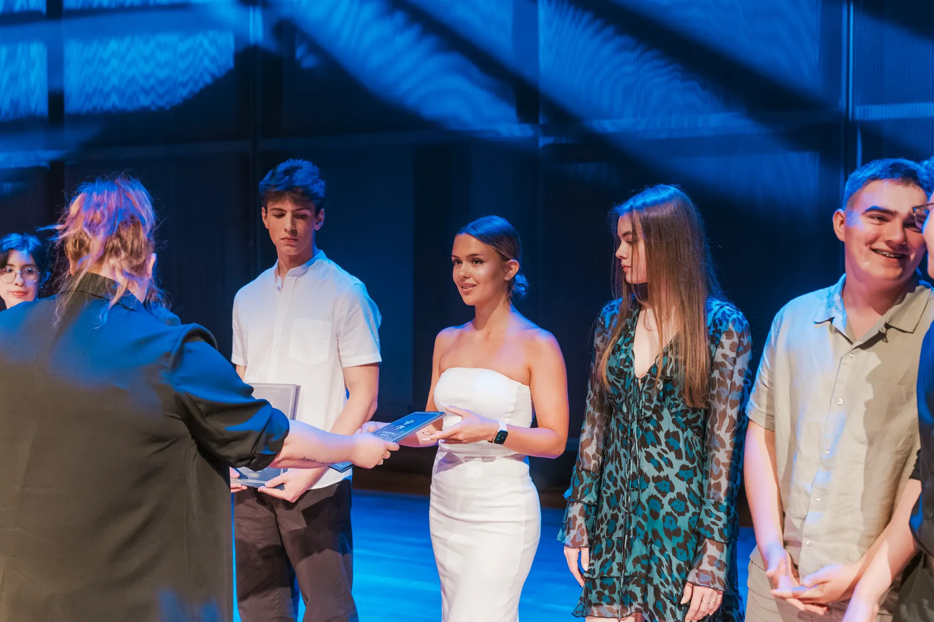 Students of the International American School of Warsaw receiving certificates on stage
