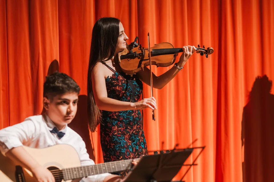 IAS students playing violin and guitar on stage
